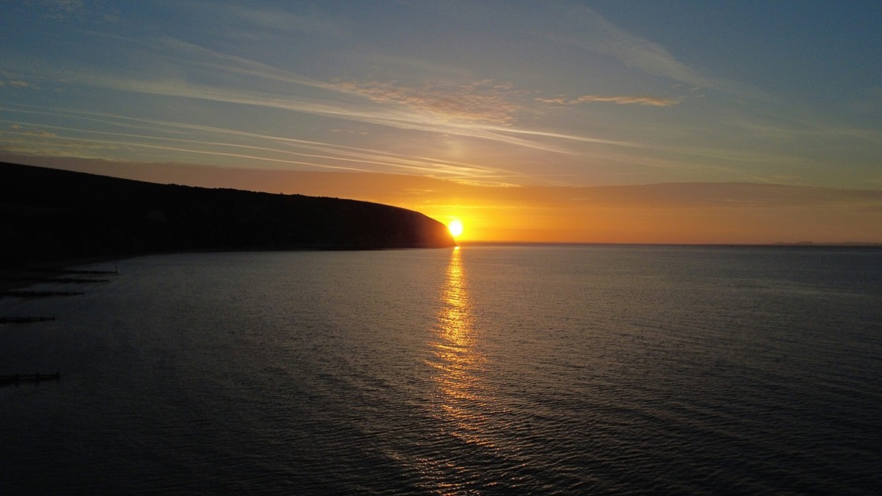 Golden sunset light opening across a calm, endless ocean